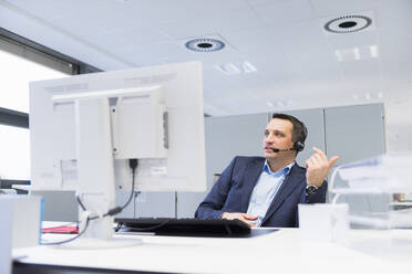 Businessman with headset sitting at desk in office - DIGF11523