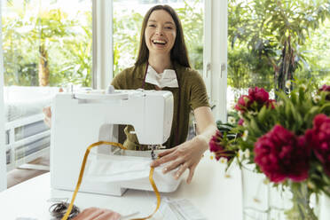 Portrait of happy woman sewing face masks at home - MFF05660