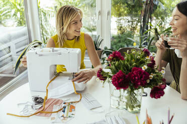 Woman with friend sewing face masks at home - MFF05663