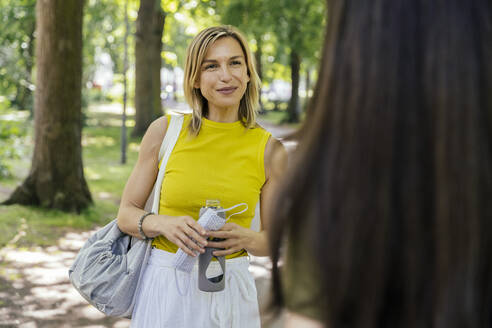 Frau trifft ihren Freund in der Natur und hält eine Gesichtsmaske - MFF05688