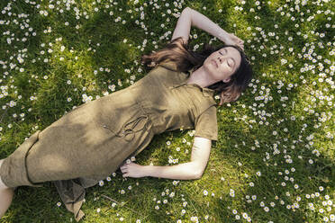 Woman enjoying her free time while lying on grass with daisies - MFF05704