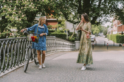 Two women with bicycle and face mask walking on a bridge - MFF05751