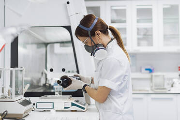 Doctor pouring chemical in beaker on weight scale while doing research in laboratory - OCAF00512