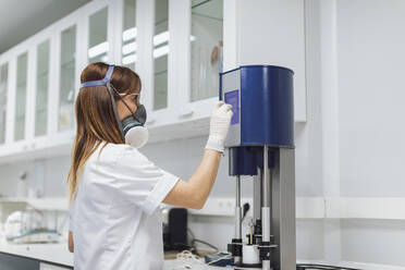 Confident female healthcare worker using medical equipment at laboratory - OCAF00526