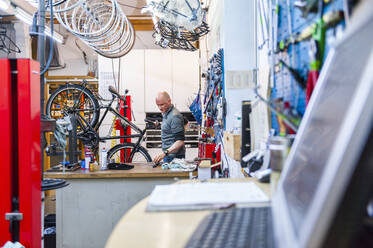 Bicycle mechanic working in bike shop - DIGF11578