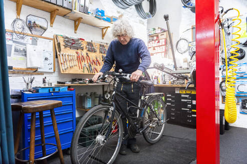 Fahrradmechaniker bei der Arbeit in einer Fahrradwerkstatt, Überprüfung der Bremsen - DIGF11594