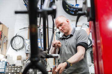 Bicycle mechanic working in bike shop - DIGF11598