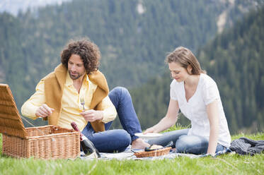 Mid adult couple enjoying picnic against mountain - DIGF11635