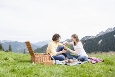 Mid adult couple enjoying picnic on grass against clear sky - DIGF11636