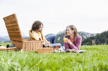 Mid adult couple enjoying picnic while lying against clear sky - DIGF11640