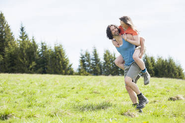 Mann trägt seine Frau im Sommer auf dem Rücken, Wallberg, Bayern, Deutschland - DIGF11677