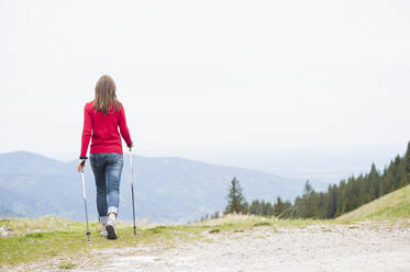 Rückansicht einer Frau mit Wanderstöcken - DIGF11678