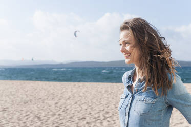 Porträt einer glücklichen Frau mit wehendem Haar am Strand, Sardinien, Italien - DIGF11684