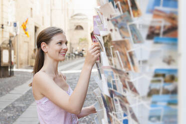 Porträt eines Touristen, der in der Stadt Postkarten auswählt, Sardinien, Italien - DIGF11706