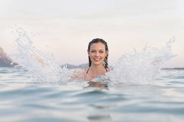 Porträt einer glücklichen Frau, die mit Wasser plantscht, Sardinien, Italien - DIGF11722