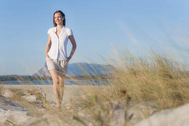Porträt einer lächelnden Frau, die in den Stranddünen spazieren geht, Sardinien, Italien - DIGF11752