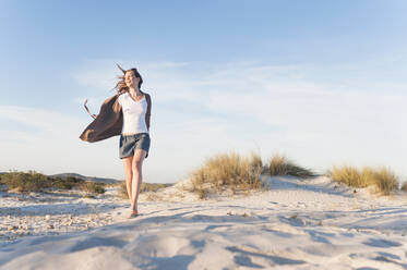 Happy woman strolling through beach dunes, Sardinia, Italy - DIGF11766