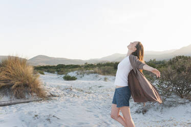 Happy woman relaxing in beach dunes, Sardinia, Italy - DIGF11768