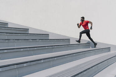 Sportsman wearing face mask running up stairs - AHSF02622