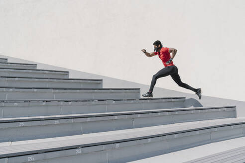 Sportler mit Gesichtsmaske läuft eine Treppe hinauf - AHSF02623