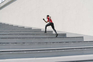 Sportsman wearing face mask running up stairs - AHSF02624