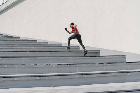 Sportler mit Gesichtsmaske läuft eine Treppe hinauf - AHSF02624