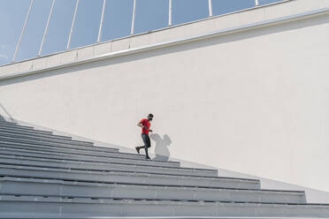 Sportsman wearing mask running down stairs - AHSF02625