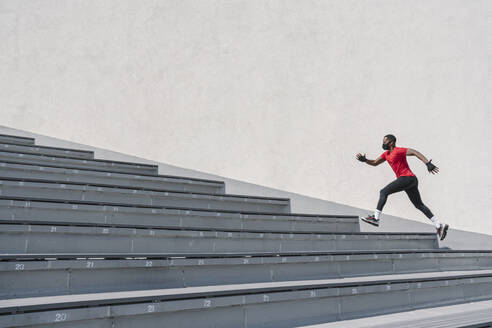 Sportler mit Gesichtsmaske läuft eine Treppe hinauf - AHSF02632