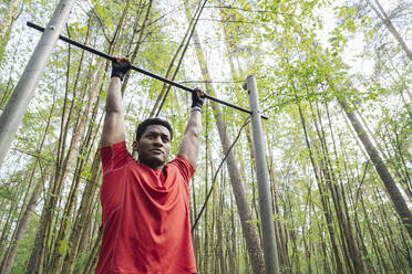 Sportsman exercising at high bar in the forest - AHSF02651