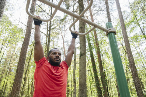 Sportler beim Üben am Klettergerüst im Wald, lizenzfreies Stockfoto