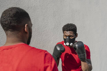 Sportsman wearing face mask and boxing against training partner - AHSF02681