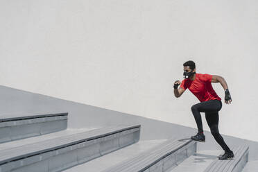 Sportler mit Gesichtsmaske läuft eine Treppe hinauf - AHSF02685