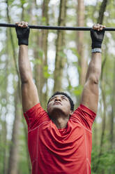 Sportsman exercising at high bar in the forest - AHSF02695