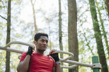 Sportsman exercising at climbing frame in the forest - AHSF02697