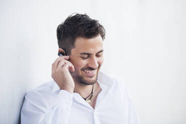 Businessman with earphone on white wall - DIGF11775