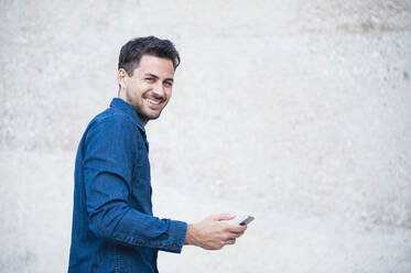 Smiling young man with smartphone - DIGF11791