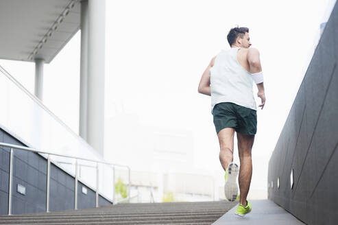 Rückansicht eines jungen Mannes beim Joggen in der Stadt - DIGF11792