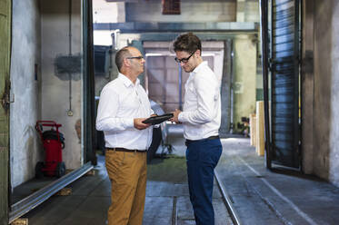 Zwei Geschäftsleute bei einem Treffen in einer Fabrikhalle - DIGF11812