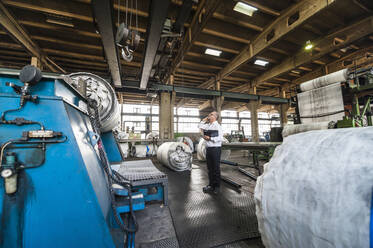 Senior businessman on the phone in a factory hall - DIGF11848