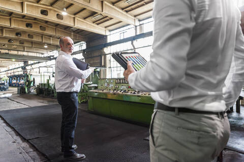 Two businessmen having a meeting in a factory hall stock photo