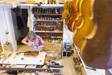 Female violin maker at work in her workshop - DIGF11881