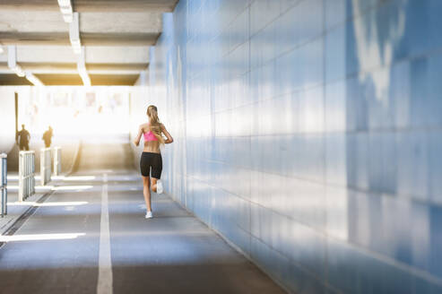 Rückansicht einer Joggerin im Tunnel - DIGF11906