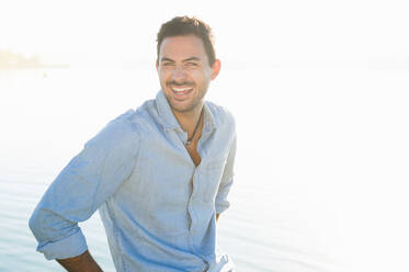 Porträt eines lachenden jungen Mannes vor einem See - DIGF11914