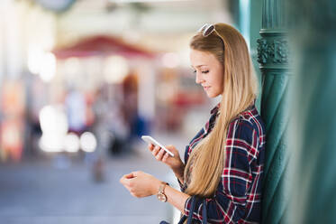 Young woman leaning against column looking at smartphone - DIGF11993