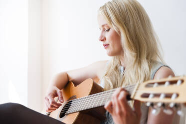 Portrait of blond woman playing guitar - DIGF12011