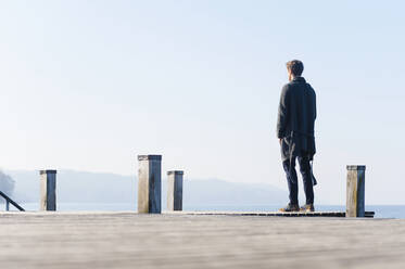 Man looking at lake against clear sky while standing on pier during sunny day - DIGF12056