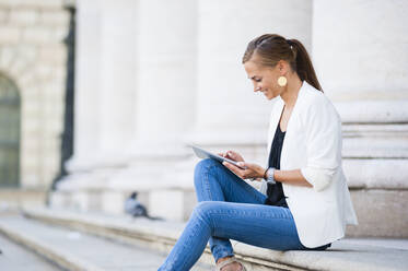 Lächelnde Frau, die in der Stadt ein digitales Tablet benutzt - DIGF12065