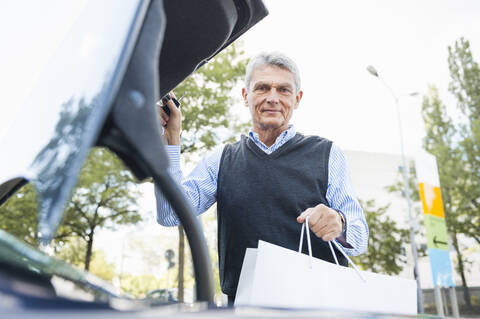 Portrait of senior man loading shopping bag into car stock photo