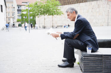 Senior businessman reading newspaper outdoors - DIGF12093