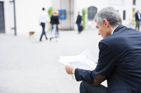 Senior businessman reading newspaper outdoors stock photo